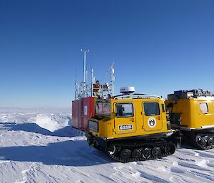 Expeditioner atop a container with aerials in background with yellow tracked vehicle in foreground