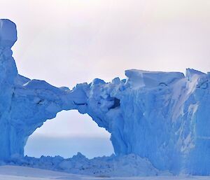 Ice berg stuck in the sea ice with a natural arch in the middle