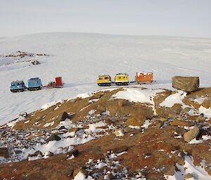 Two tracked vehicles in procession moving down an ice ramp