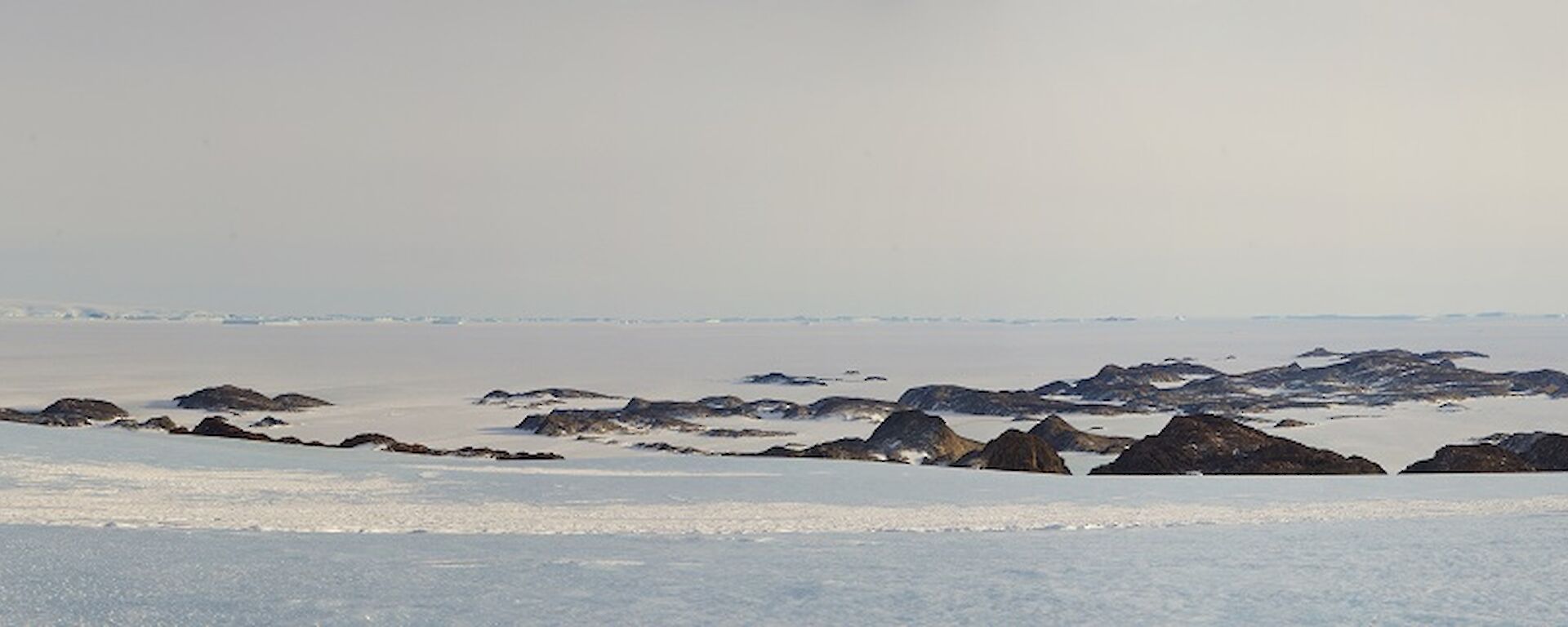 Panoramic photo of large glacier, sea ice and brown islands