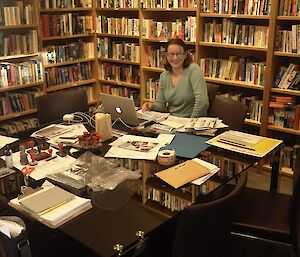 Expeditioner smiling at camera seated behind a table covered in stationary