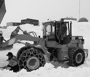 Expeditioner standing on a mechanical loader carrying a large container. Station in background