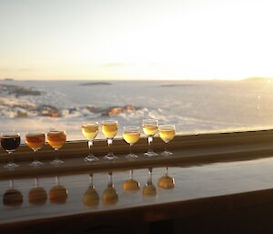 A mix of beers in small glasses perched on the window sill