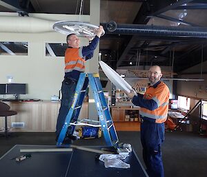 Two expeditioners, one on a ladder replacing light bulbs