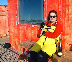 Expeditioner seated on the deck at Brookes Hut