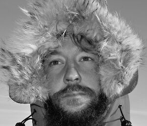 Bearded male expeditioner portrait — face surrounded by furry hood