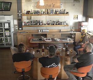 Expeditioners seated around a bar view the AFL grandfinal on a television set in the top left corner of the room