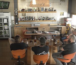 Expeditioners seated around a bar view the AFL grandfinal on a television set in the top left corner of the room