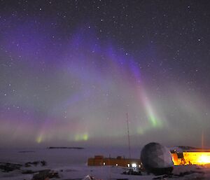 Blue and green auroras hanging in the night sky above Davis