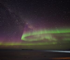 Night time shot of sea ice beside Davis station with green aurora in sky