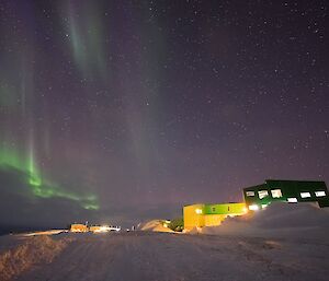 Green aurora hanging in the nights sky over station buildings