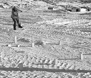 Expeditioner standing on snow throws a wooden block during a game of Kubb