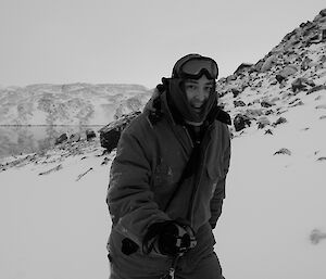 Expeditioner in cold weather clothing walking with lake and snow covered landscape in background