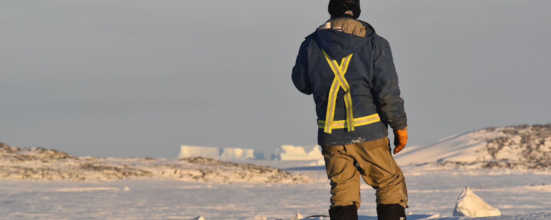 Expeditioner standing back to camera with sea ice in background