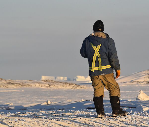 Expeditioner standing back to camera with sea ice in background