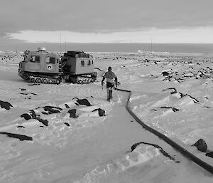 Expeditioner walking along the hose towards a tracked vehicle