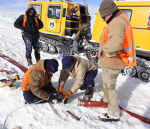 Four expeditioners gathered next to a water hose