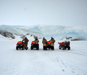 Four expeditioners pose next to their quad bikes