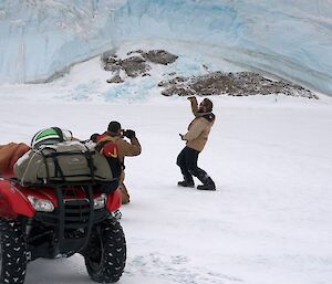Expeditioner posing for a photograph in front of an ice plateau as another expeditioner takes his photo
