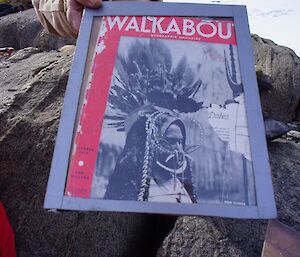 Faded old red magazine perched on top of rock surface