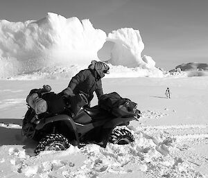 Expeditioner standing beside a bogged quad bike with an ice berg and penguin in background