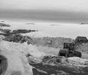 Mechanical digger shoveling snow out the front of the living quarters