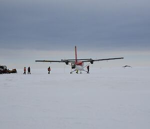 Vehicles parked close to an aeroplane with individuals walking around the aircraft