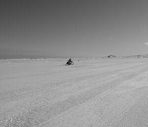 Expeditioner on a skidoo driving along an ice landing strip for aircraft