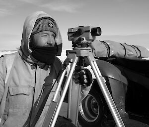 Expeditioner looking through a piece of survey equipment