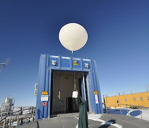 Expeditioner in green protective clothing releasing a hydrogen balloon