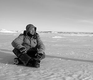 Expeditioner sitting cross legged on sea ice