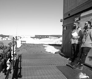 Two expeditioners leaning against a container