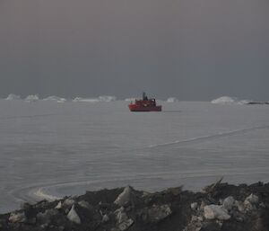 Red ship parked in sea ice off station