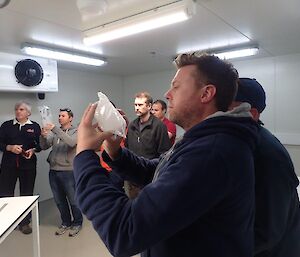 Standing in a freezer, a few expeditioners are handing parts of an ice core in baggies to inspect