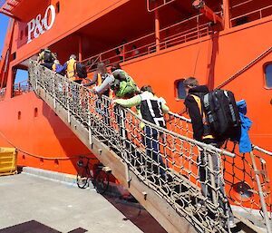 Expeditioners walk up the gangplank of the Aurora Australis with gear