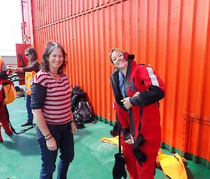 Two women don dry suits on the deck of the Aurora Australis icebreaker during a drill.