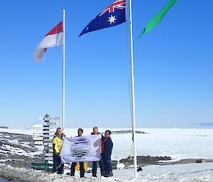 Indosian delegates and the station leader posing for a photograph in front of their representive flags