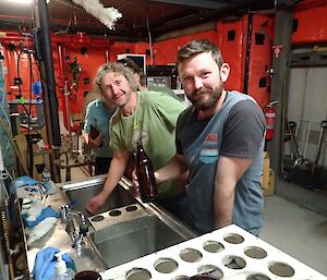 Two male expeditioners washing beer bottles