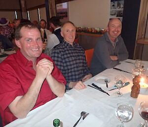 Three aircraft pilots sitting at a dinning table