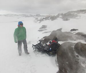 An expeditioner standing in the field in poor weather conditions