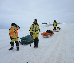 Three scientists pulling sleds along the ice