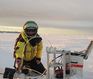 A scientists wearing a motorbike helmet on the ice testing the sea water