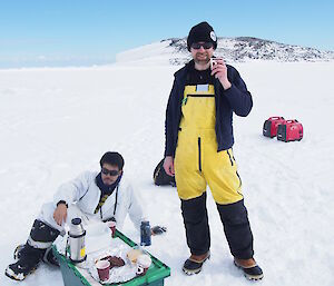 two expeditioners enjoying a bite to eat whilst on the ice