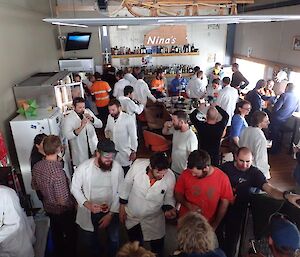 A gathering of expeditioners in the bar, the majority wearing white coats