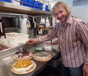 An expeditioner garnishing three pavlovas with castor sugar