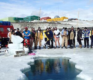 A group of expeditioners standing next to a hole in the ice