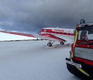 A plane and a red Hägglunds vehicle on a sea ice skiway at Davis