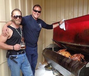 Two expeditioners cooking a spit roast