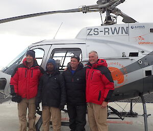 Four expeditioners standing in front of a helicopter