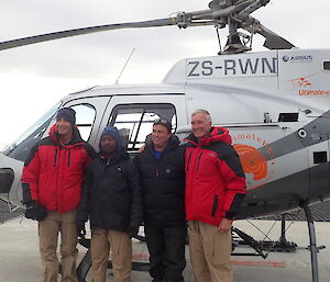 Four expeditioners standing in front of a helicopter